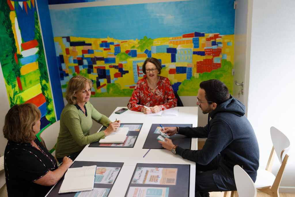 Deux formatrices accompagnent un apprenant autour d'une table dans un centre Zack Pro