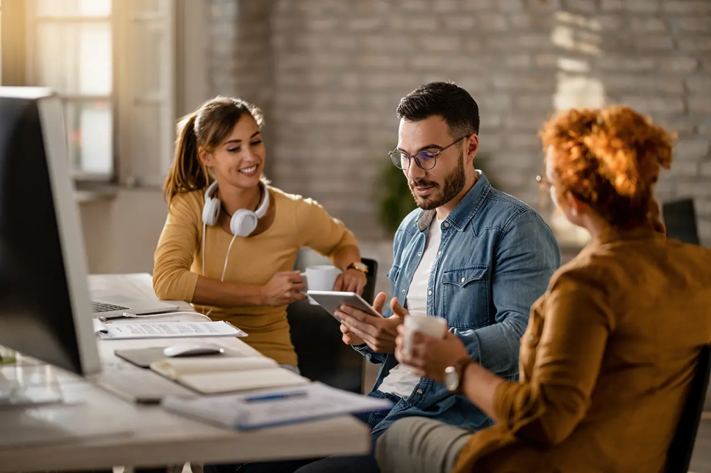 Trois collègues discutent autour d'un bureau dans un espace de travail