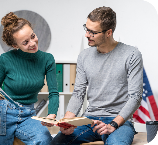 Une apprenante et un apprenant échangent autour d'un livre pendant un cours d'anglais